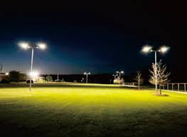 Sports field brightly illuminated by solar pole lights at night