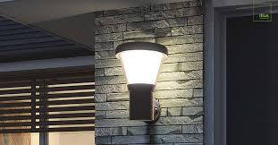 Solar wall-mount sconce on stone building